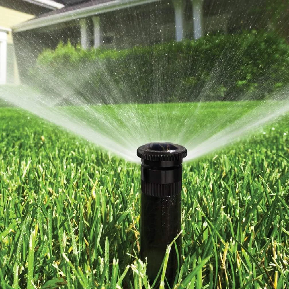 Sprinkler head watering a green lawn